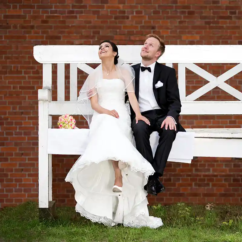 Hochzeitpaar sitzt auf einer riesigen Parkbank