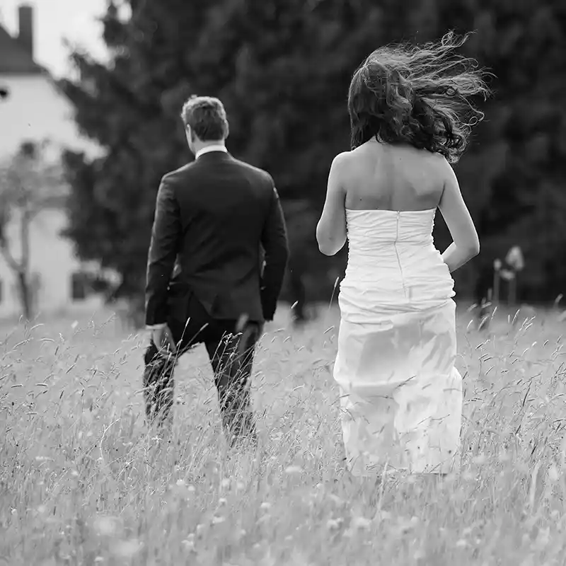 Brautpaar schreitet durch eine Wiese in schwarz-weiss