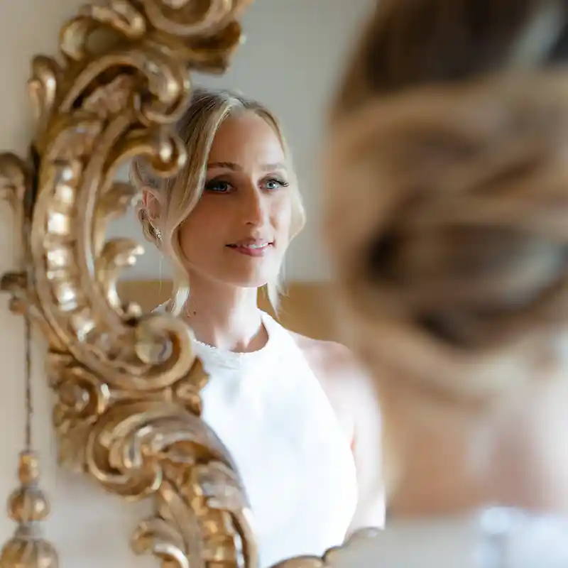 eine Braut betrachtet sich im Spiegel