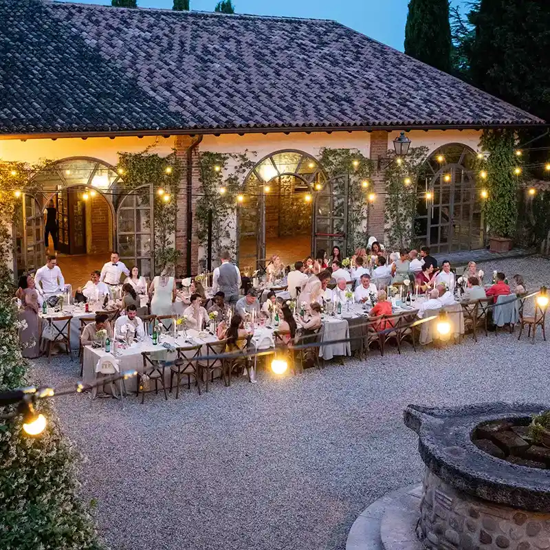 Hochzeitsgesllschaft bei Essen im Innenhof eines italienischen Landguts