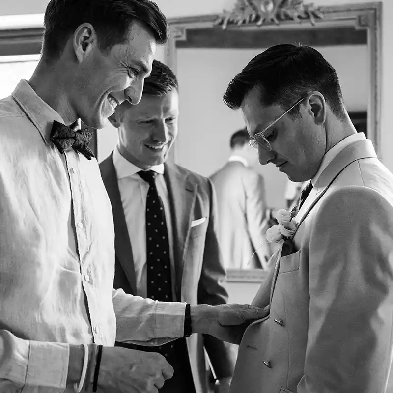 Jungesellen helfen dem Bräutigam beim Anziehen